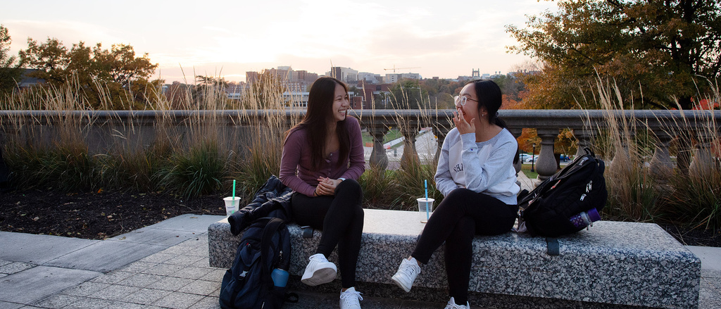 two students talking while seated near old cap