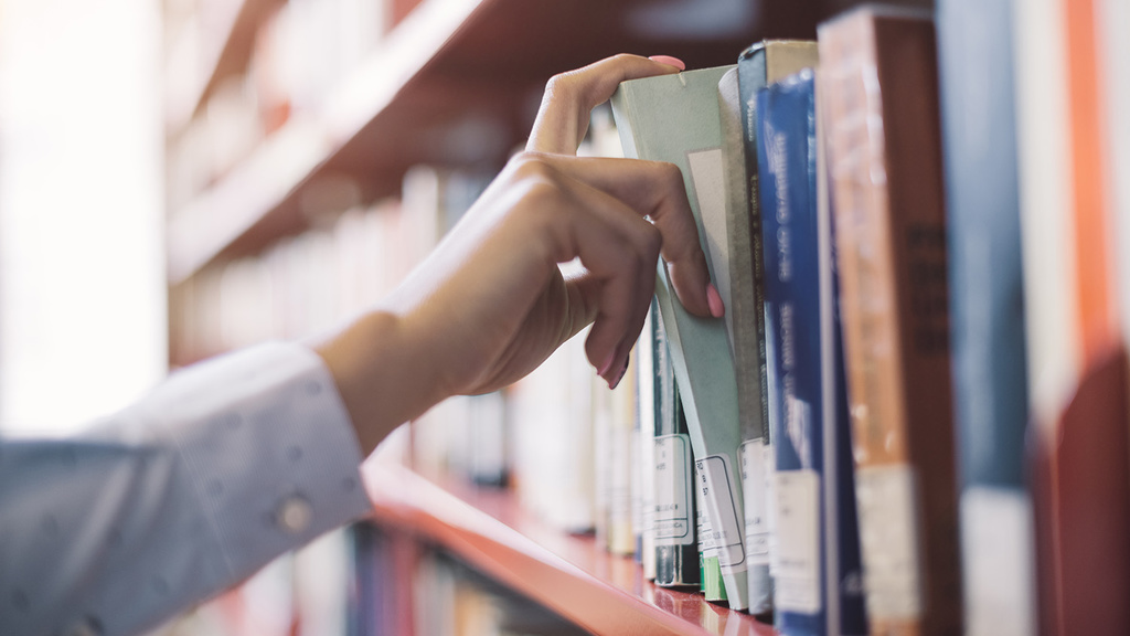 person pulling a book from a shelf