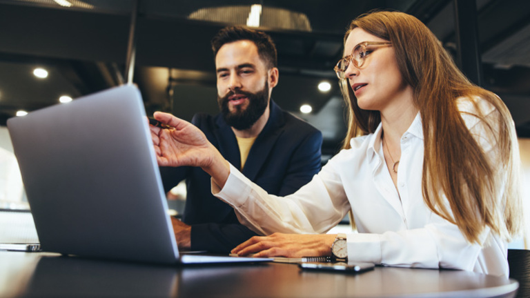 Two people working together in front of laptop